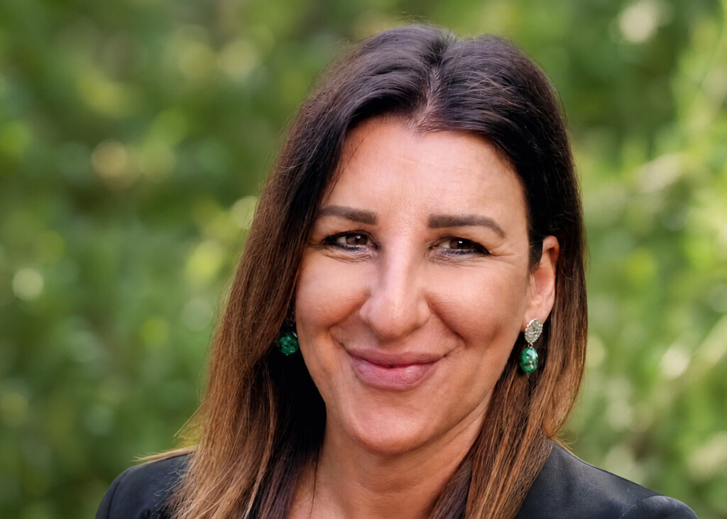 Professional portrait of Grazia Polidori against a softly blurred natural green background.